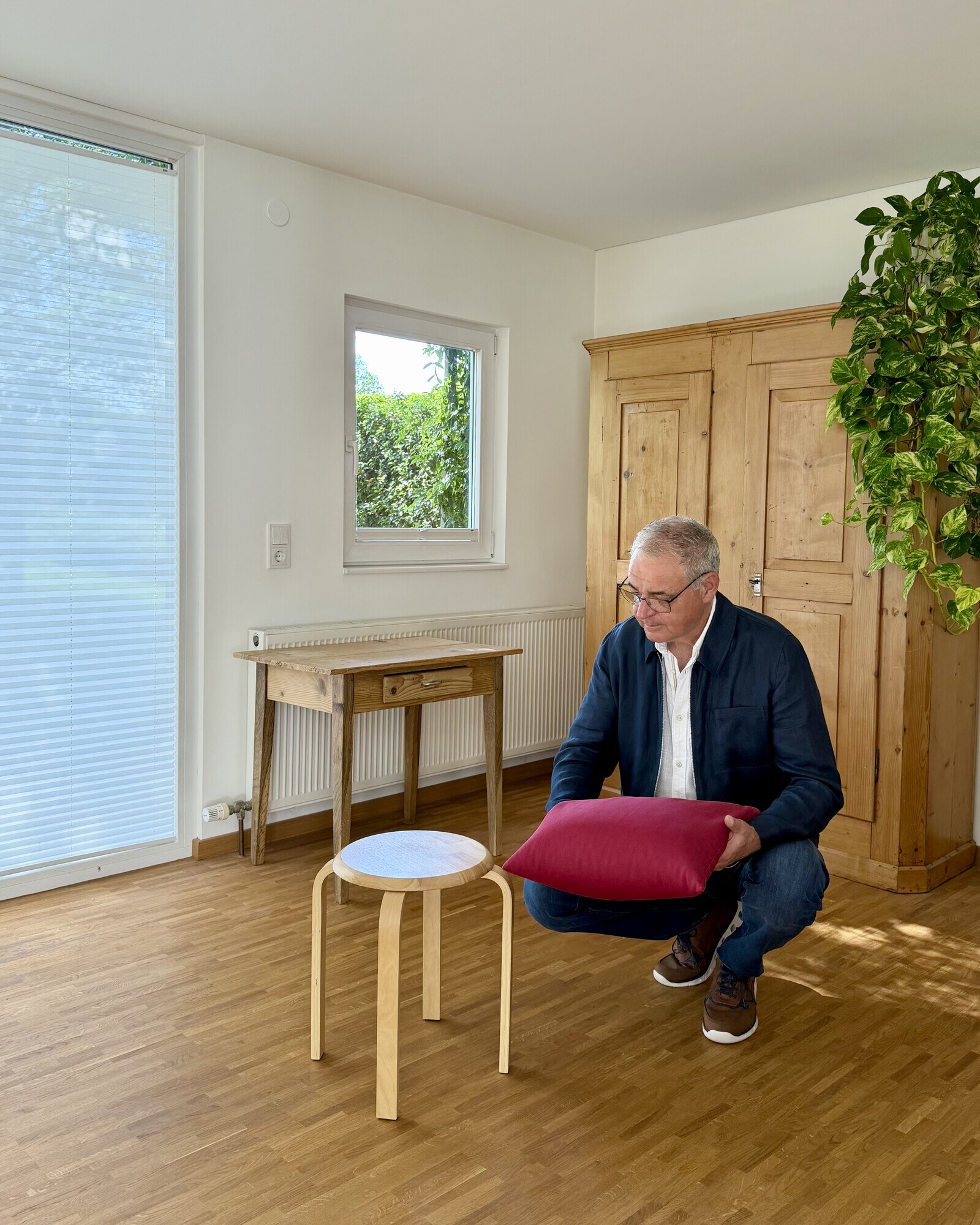 Alois Mennel arbeitet mit einem roten Kissen und einem Hocker